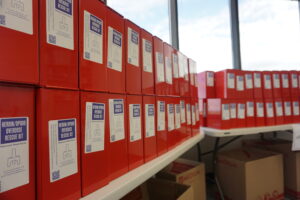 Boxed kits with naloxone, an overdose-reversal drug, and associated equipment are stacked on tables at the Alaska Department of Health's Anchorage office on Aug. 9, 2024. The kits were assembled that day in preparation for distribution to school districts around the state, in accordance with House Bill 202. (Photo by Yereth Rosen/Guardian Spotlight)